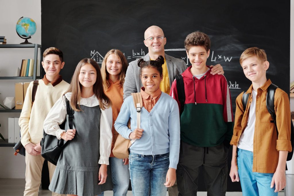 A group of diverse teenagers with backpacks and a teacher smiling in a classroom.
